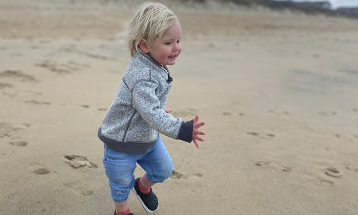 Photo of a toddler-aged patient running on a beach.