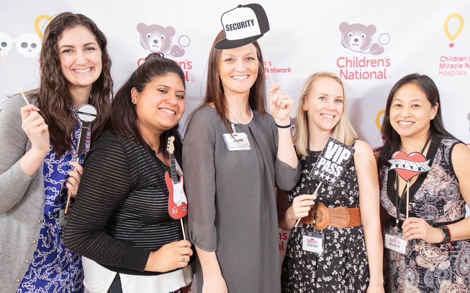 Five women pose with party props for a group photo at a Children's National fundraising event.