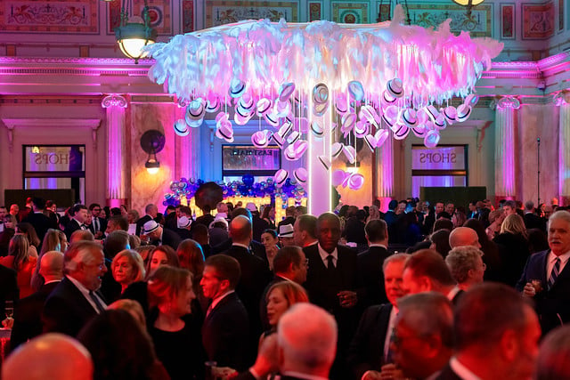 White Hat Gala attendees gathered under a chandelier of white hats