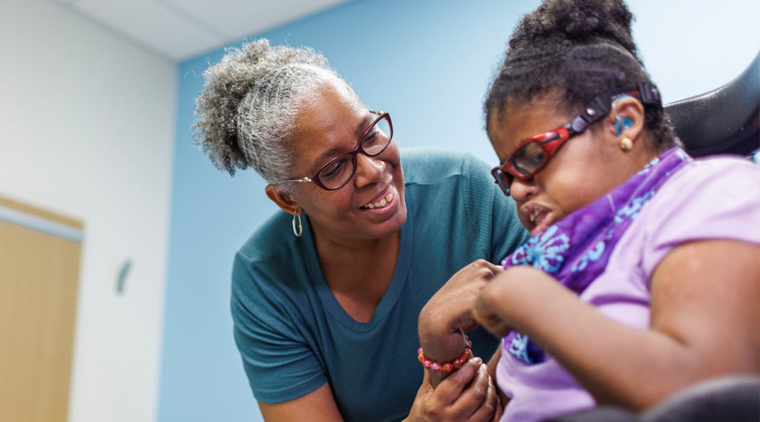 A Black female elementary school aged patient receives support from her mother.