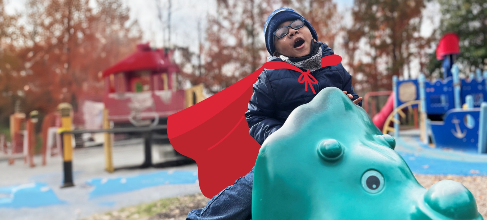 Young boy on a playground wearing a cape.