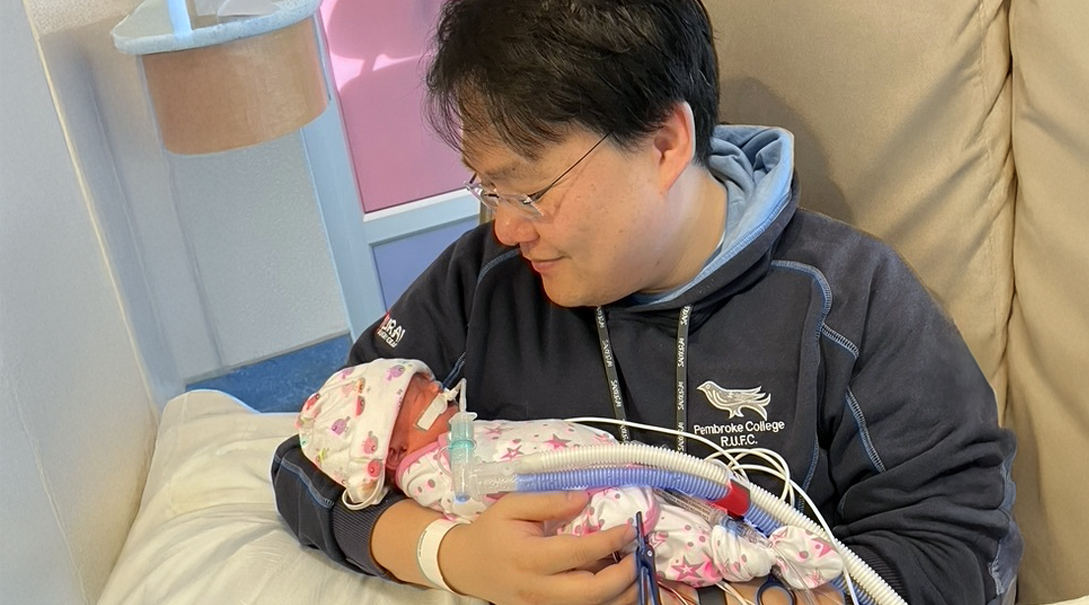 An infant patient, Abby, is held by her father while she is connected to various health monitoring devices.