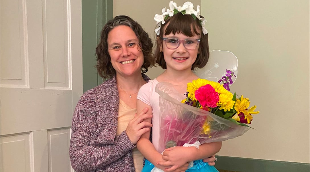 CNH patient, Emelia, standing with her mother and smiling at the camera.