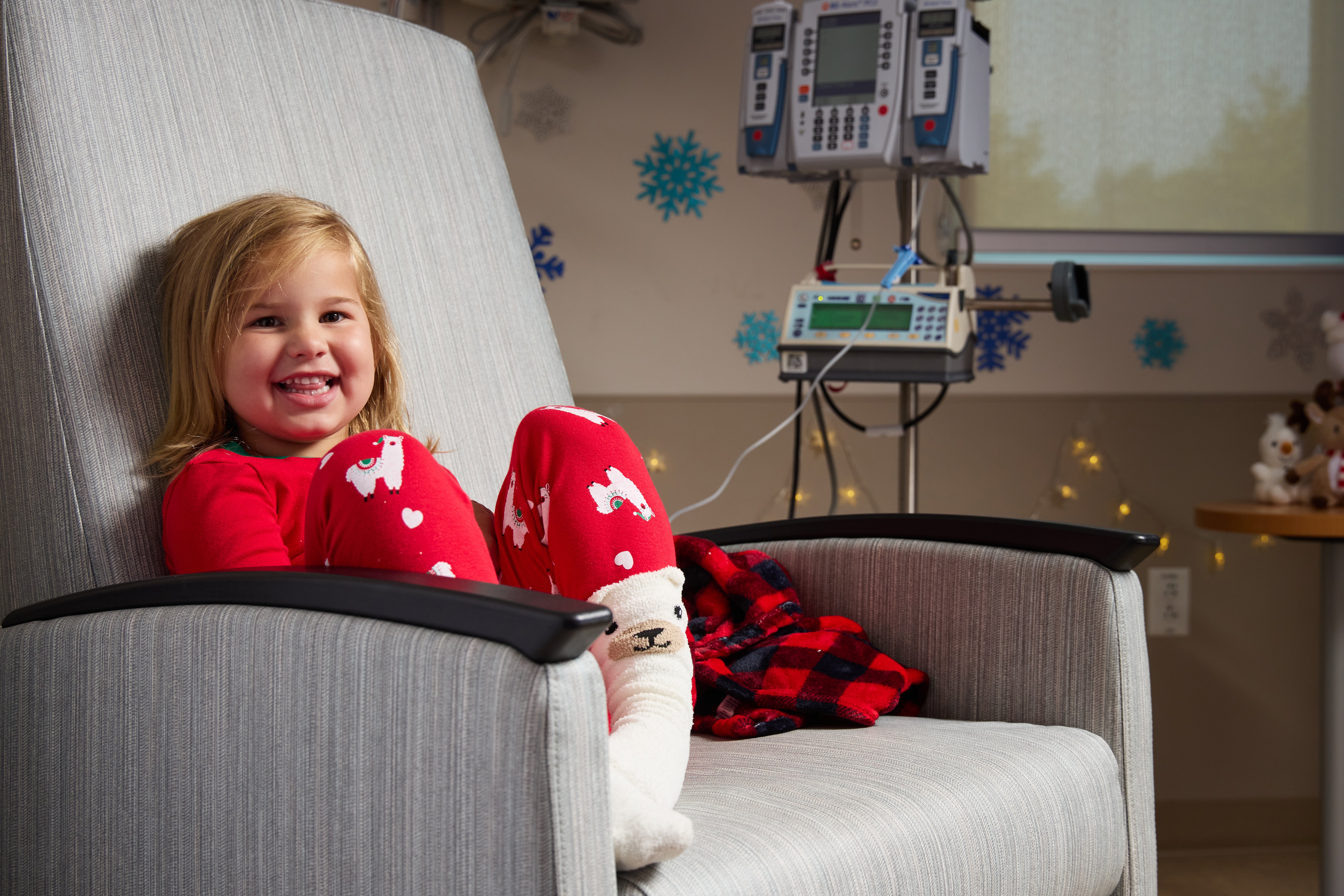 Claire, Children's National Patient, wearing red pajamas and smiling in an armchair.