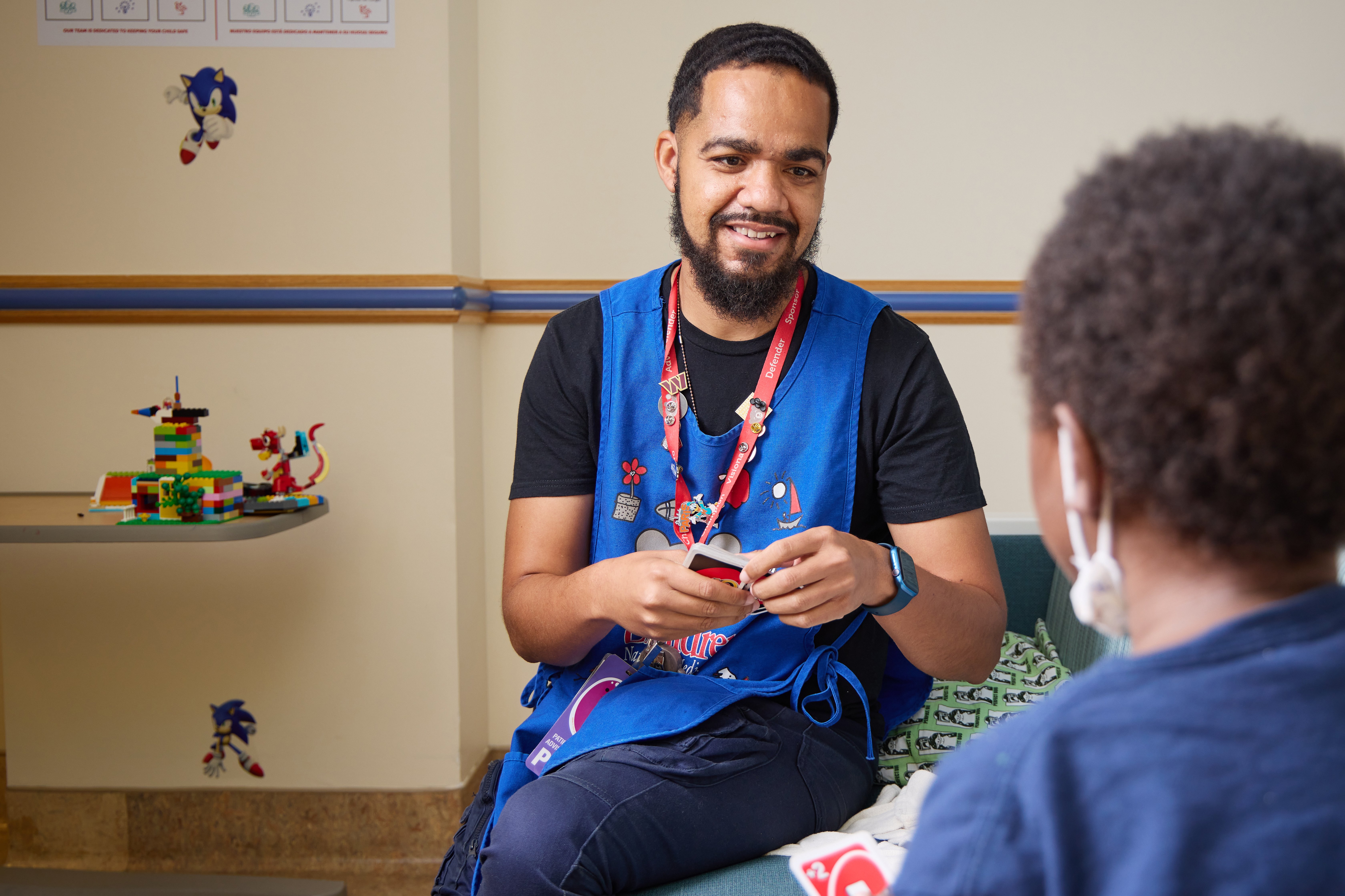 Austin, a Children's National volunteer, smiling while playing Uno with a younger patient.