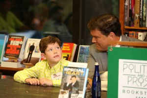 Bret Baier seated next to his son at the book signing