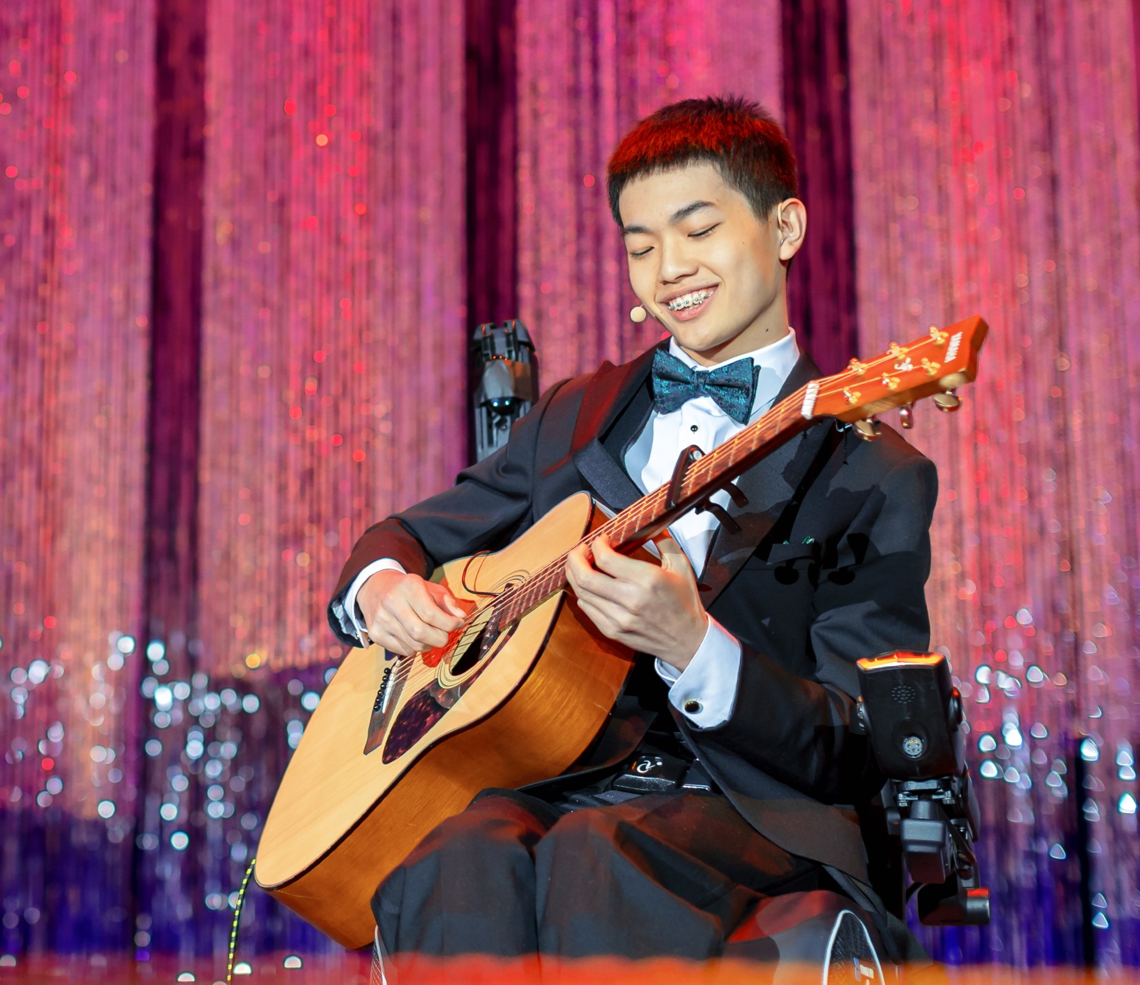 Max playing acoustic guitar at the 2025 Children's Ball.