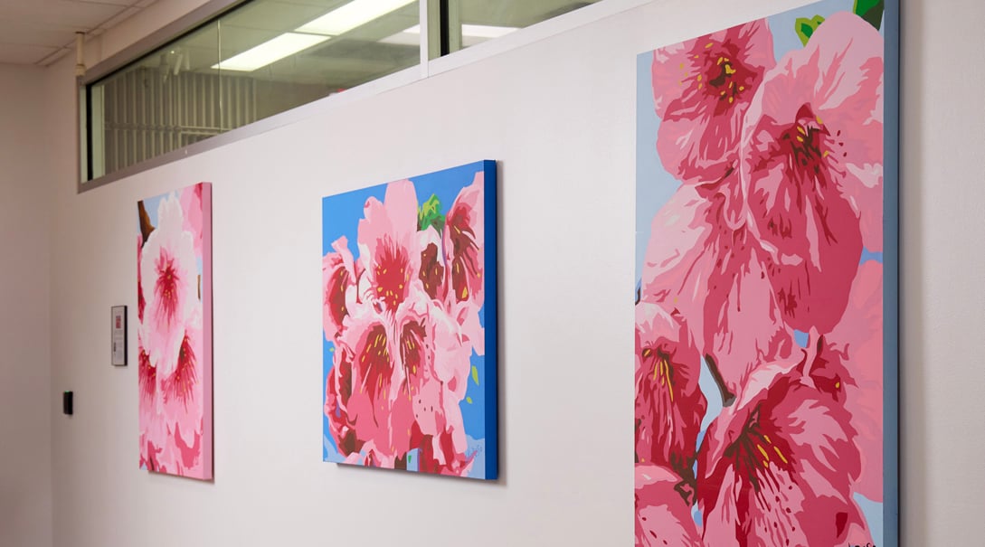 White wall featuring three paintings of pink cherry blossom flowers