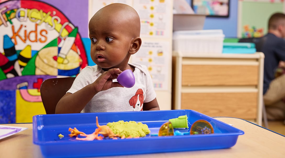 A young patient explores a tray of sensory objects in the Tracy's Kids art therapy studio.