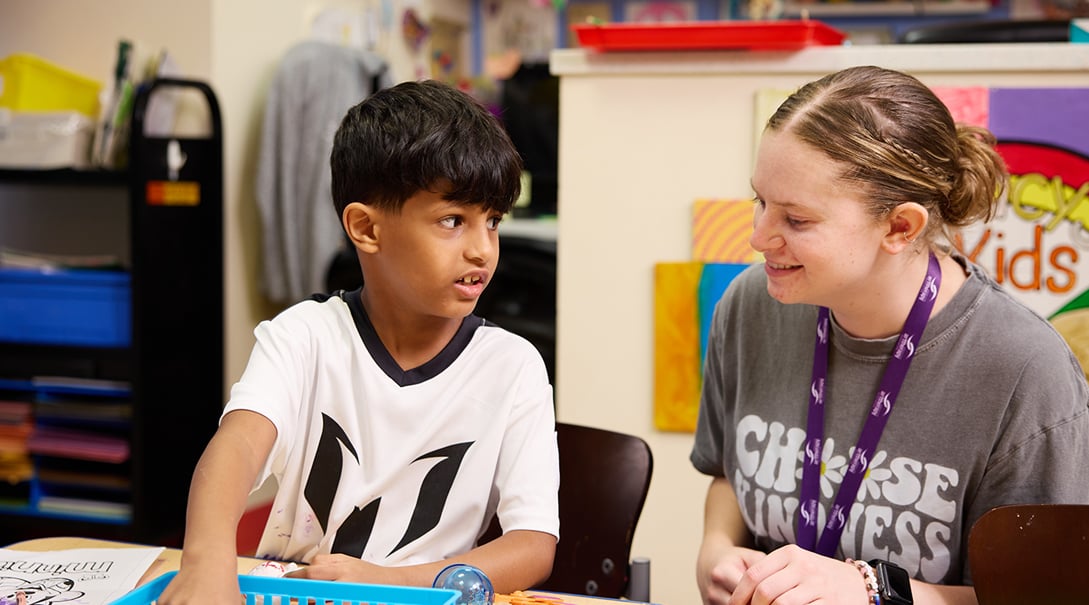 A staff member at Tracy's Kids art therapy studio engages with an adolescent visitor.