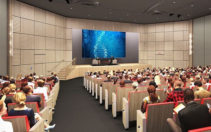 A modern auditorium filled with researchers listening to a presentation.