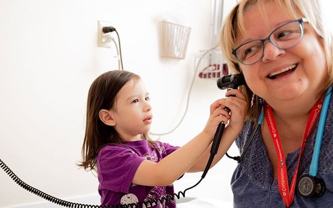 A young pre-school aged patient used her female doctor's otoscope to look in the doctor's ear.