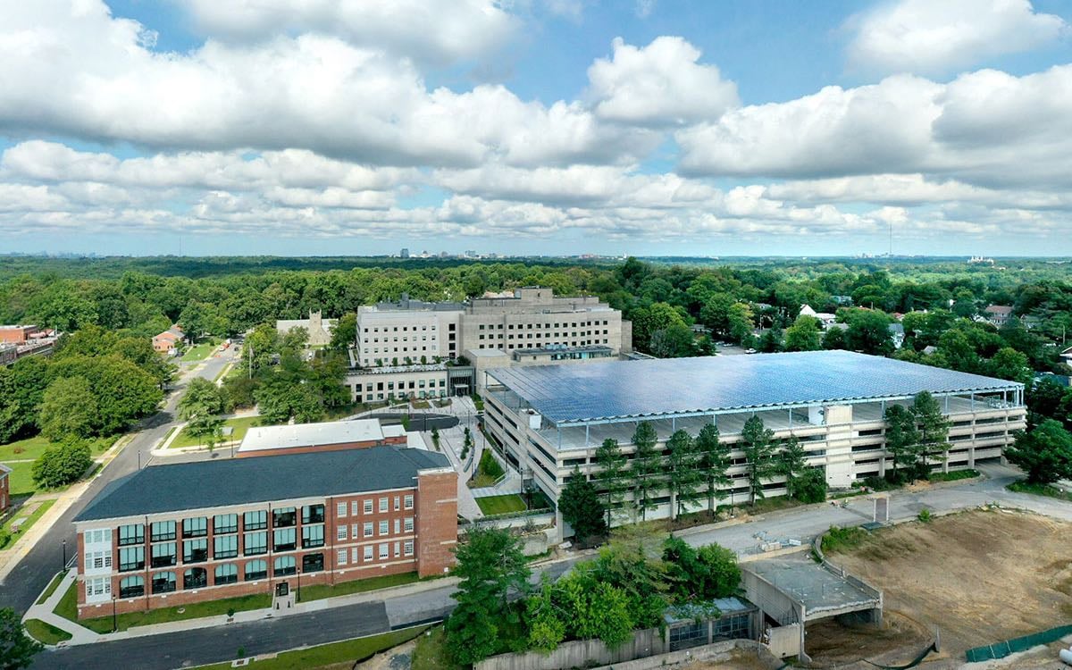 A wide shot of the Hospital's research campus featuring multiple glass and brick buildings amongst trees.