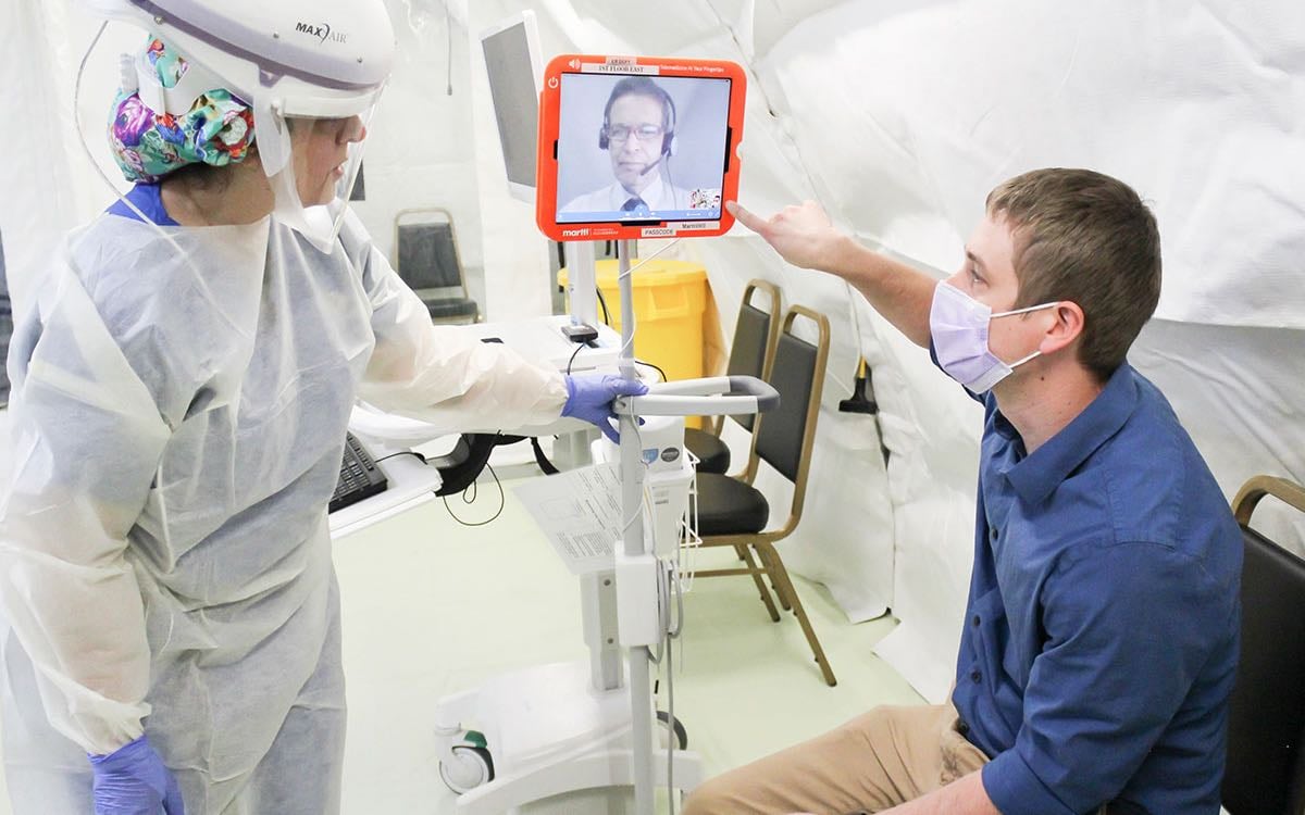 Two practitioners teleconference with a third via a tablet.