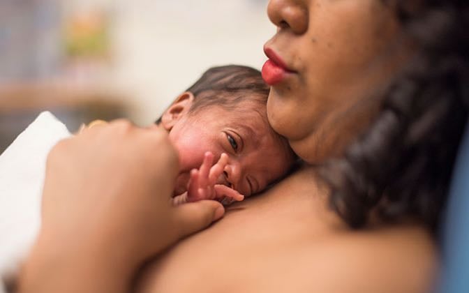 A mother holds her baby to her chest, skin to skin.