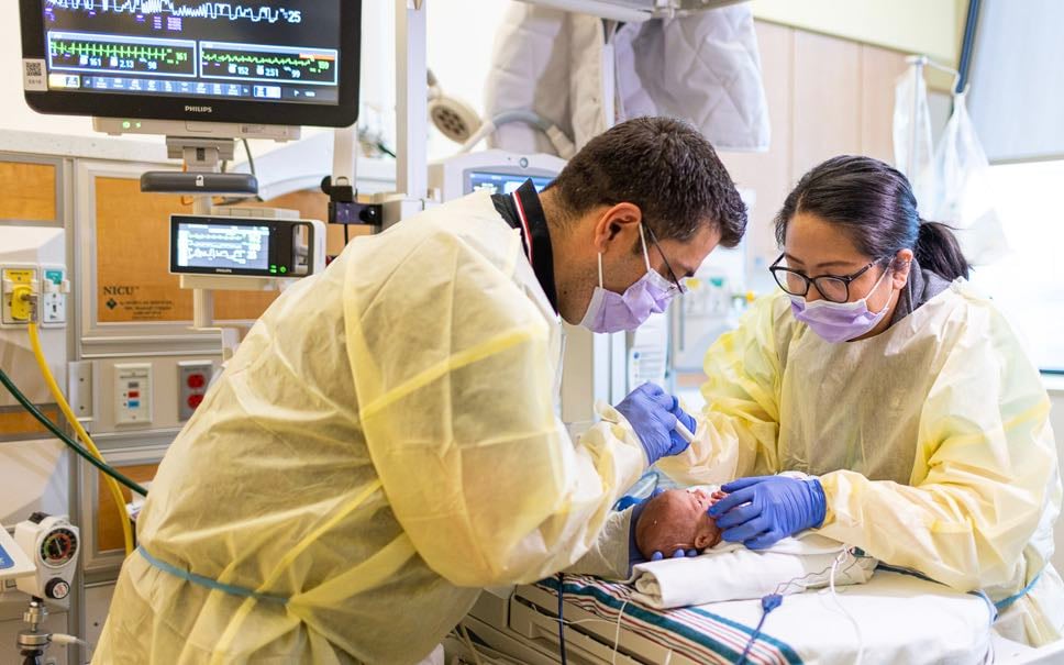 Two Children's National health professionals examine a newborn patient.