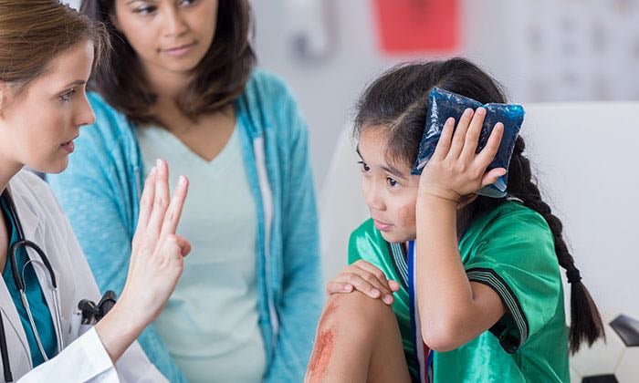 A practitioner assesses an elementary school aged patient after a sports-related head injury.
