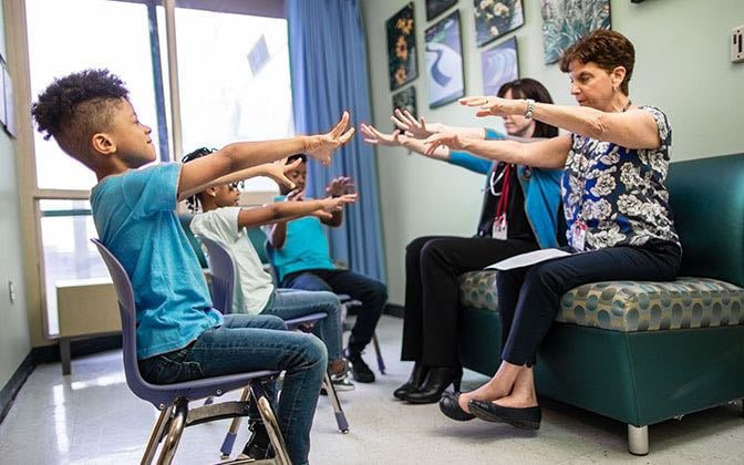 Three elementary school aged patients perform an exercise led by members of the psychiatry team.