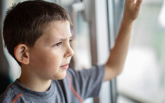 A pre-teen patient looks out of a window wistfully.