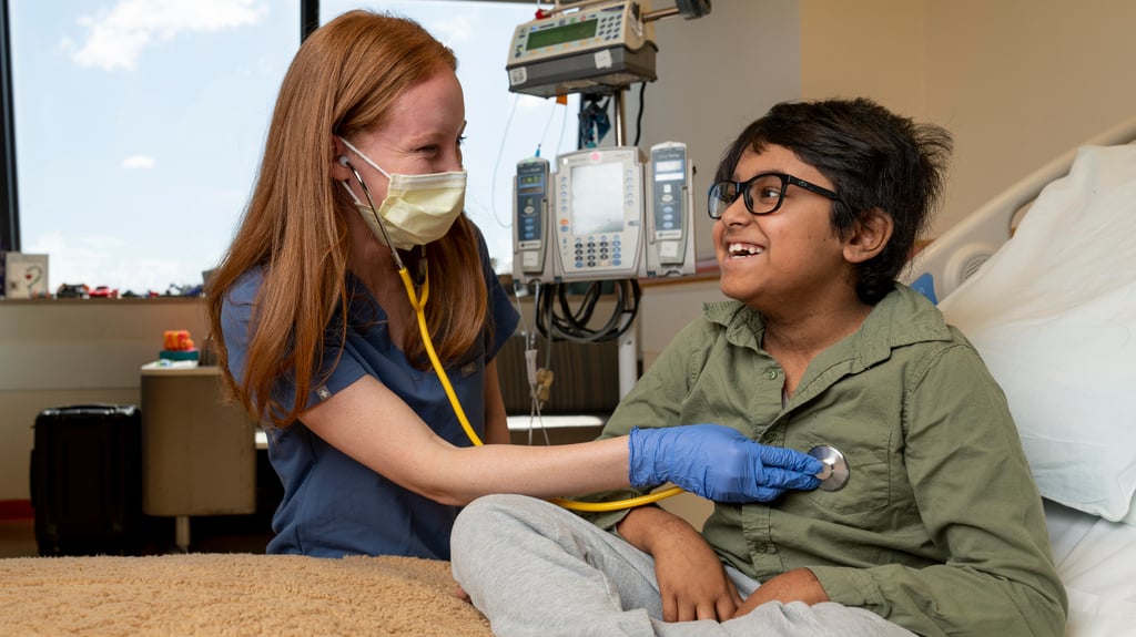 Masked smiling provider listening to smiling boy's heart