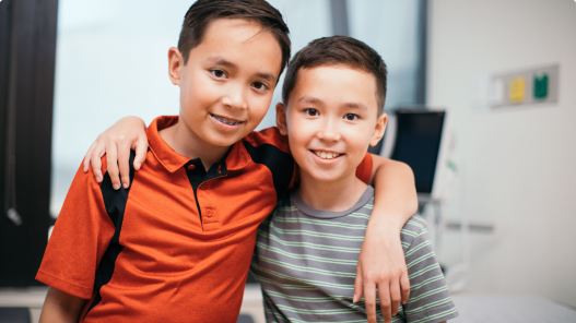 Two boys smiling with arms around each others shoulders