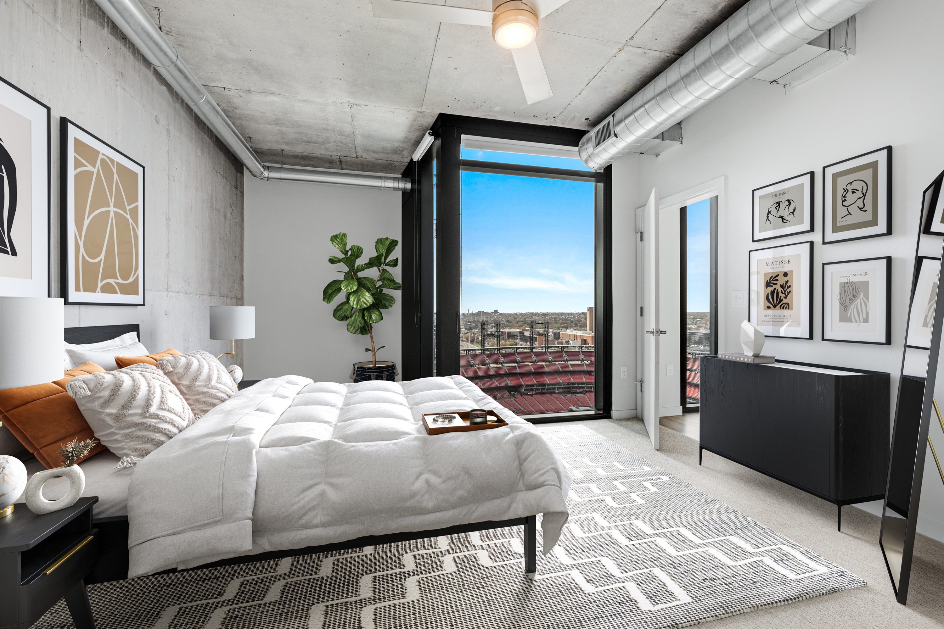 Modern apartment bedroom with floor to ceiling windows overlooking a stadium