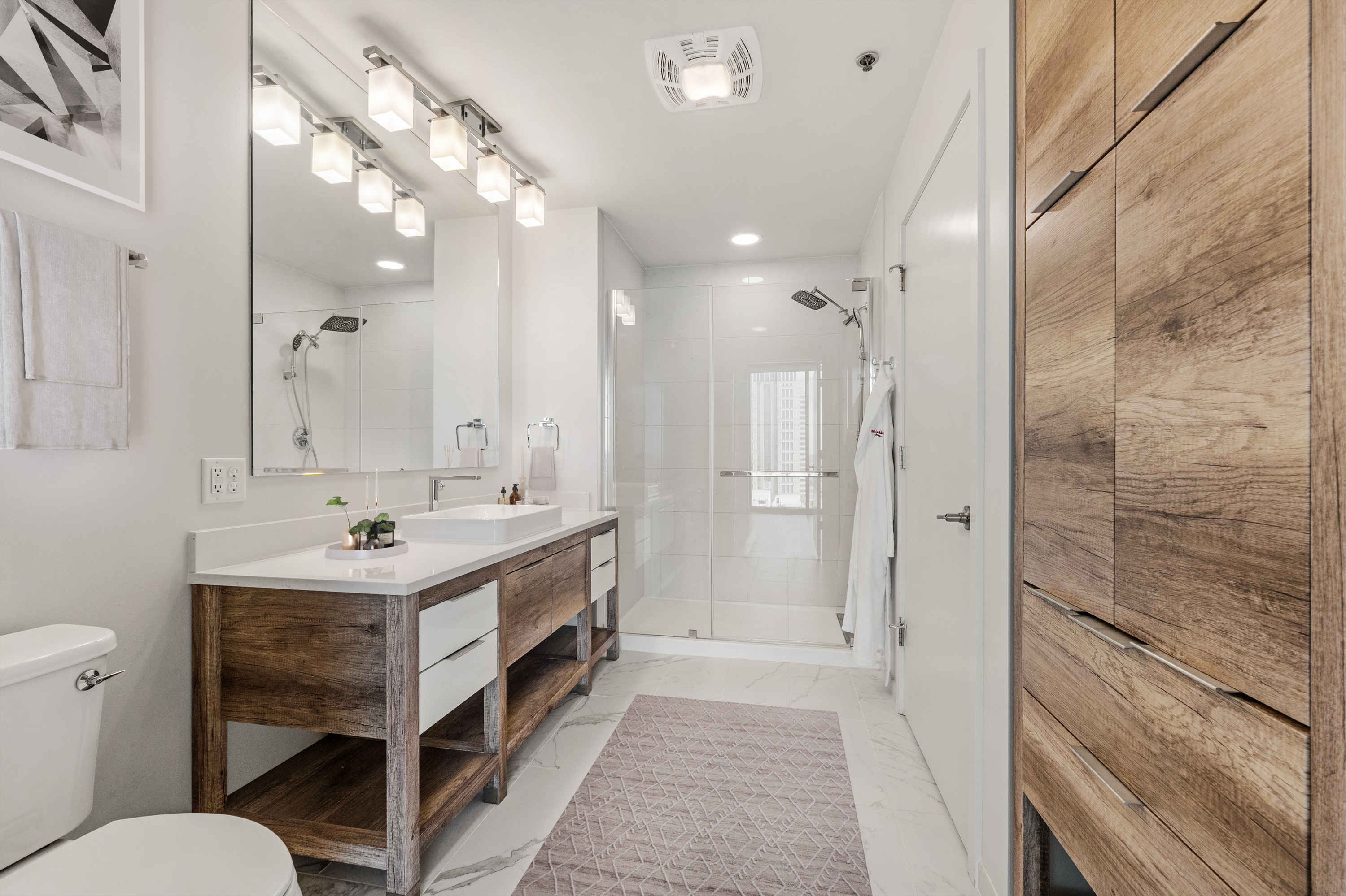 Modern bathroom with glass walk-in shower, vanity sink, and tile finishes at One Cardinal Way