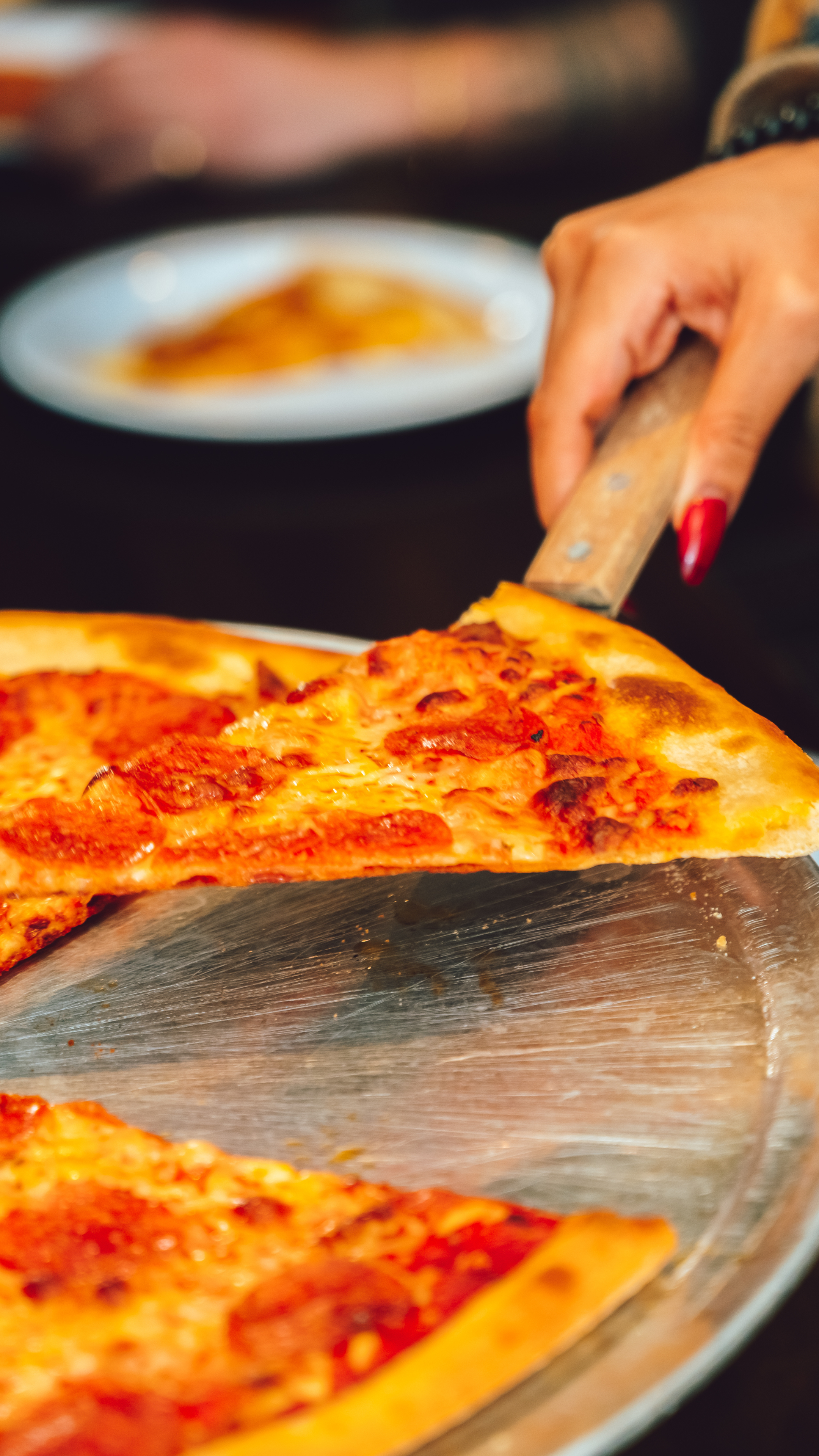 An image of someone serving a pizza slice.