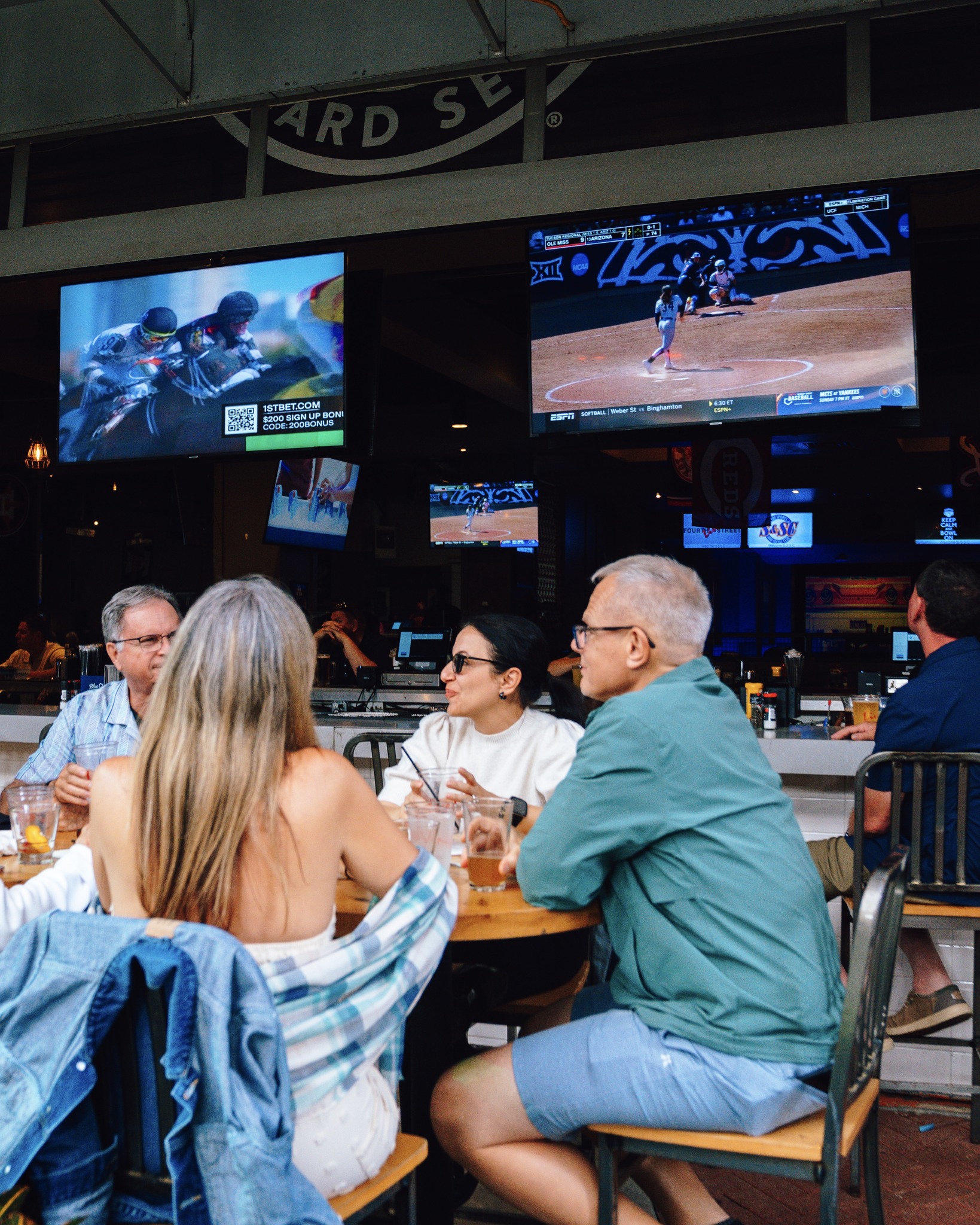 An image of people sitting at a table on the patio at Sports and Social.