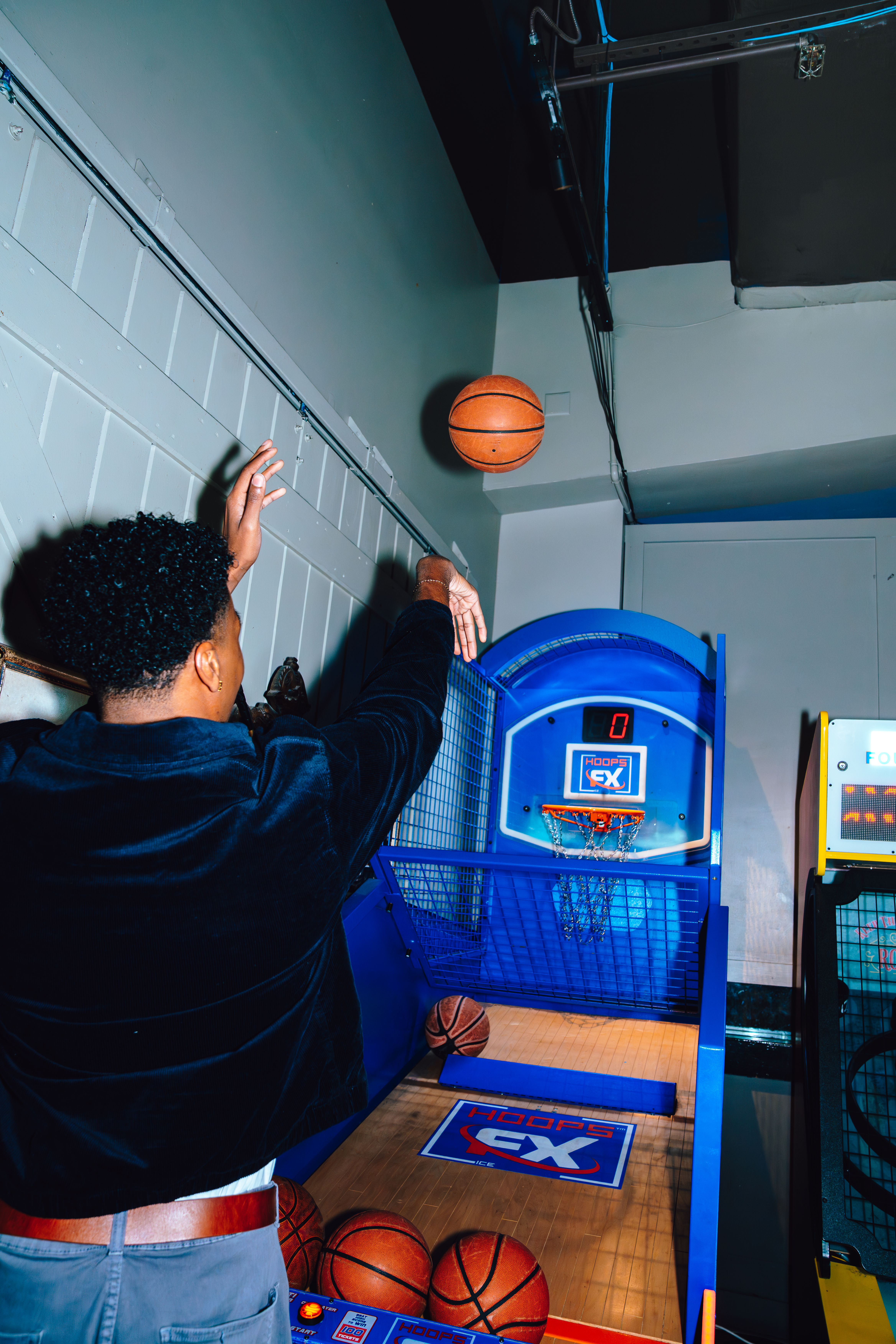 An image of a guy shooting a basketball at an arcade game.