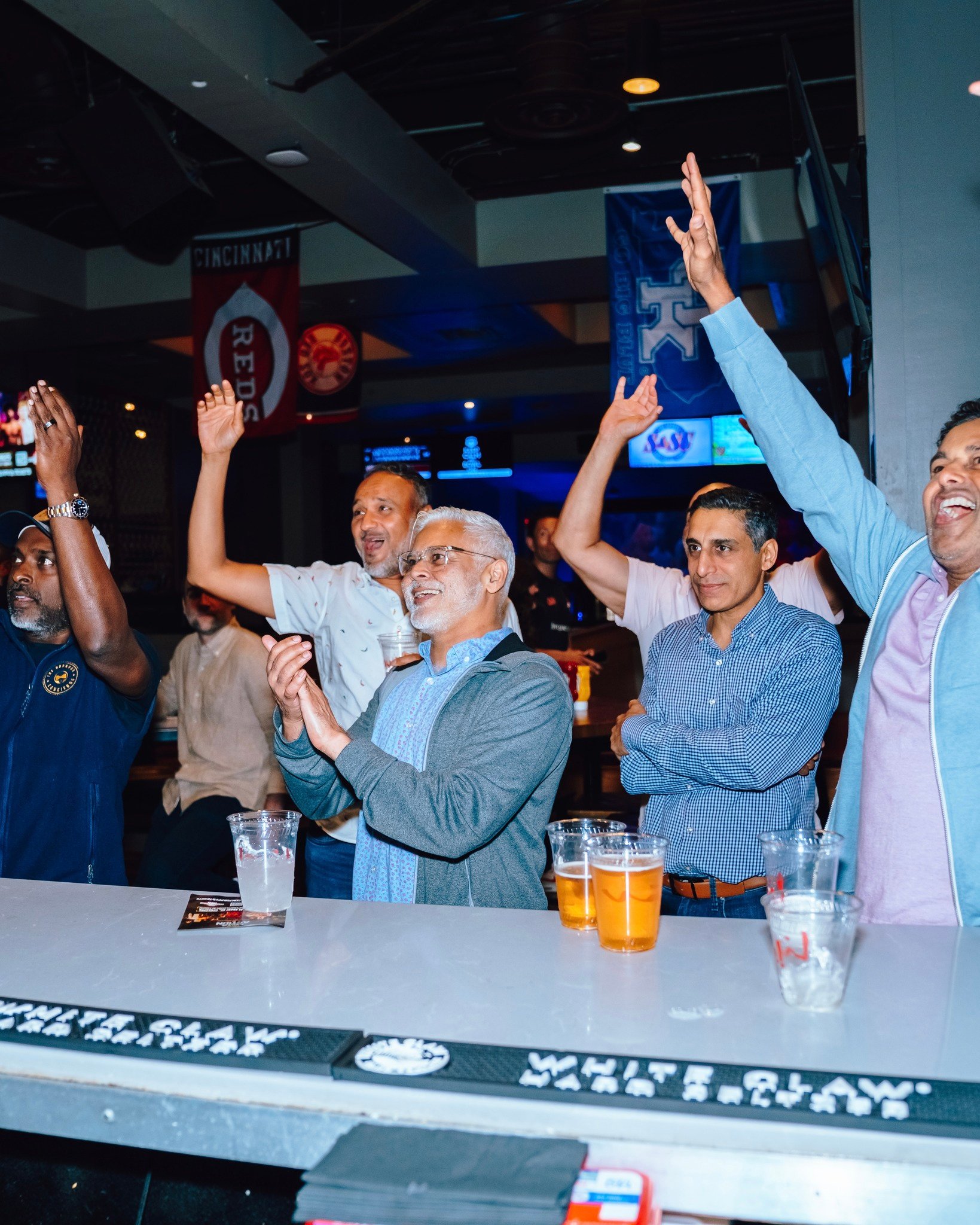 An image of fans watching sports at the bar and cheering.