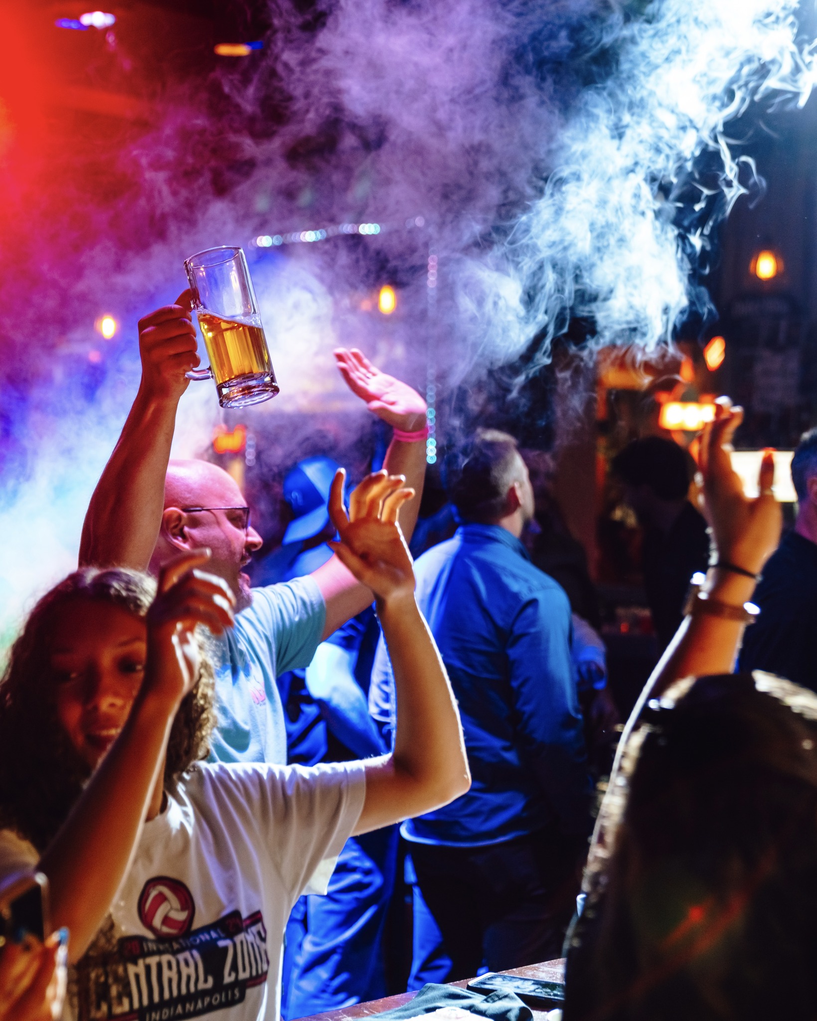 An image of people cheering with beers in hand and CO2 cannons going off.