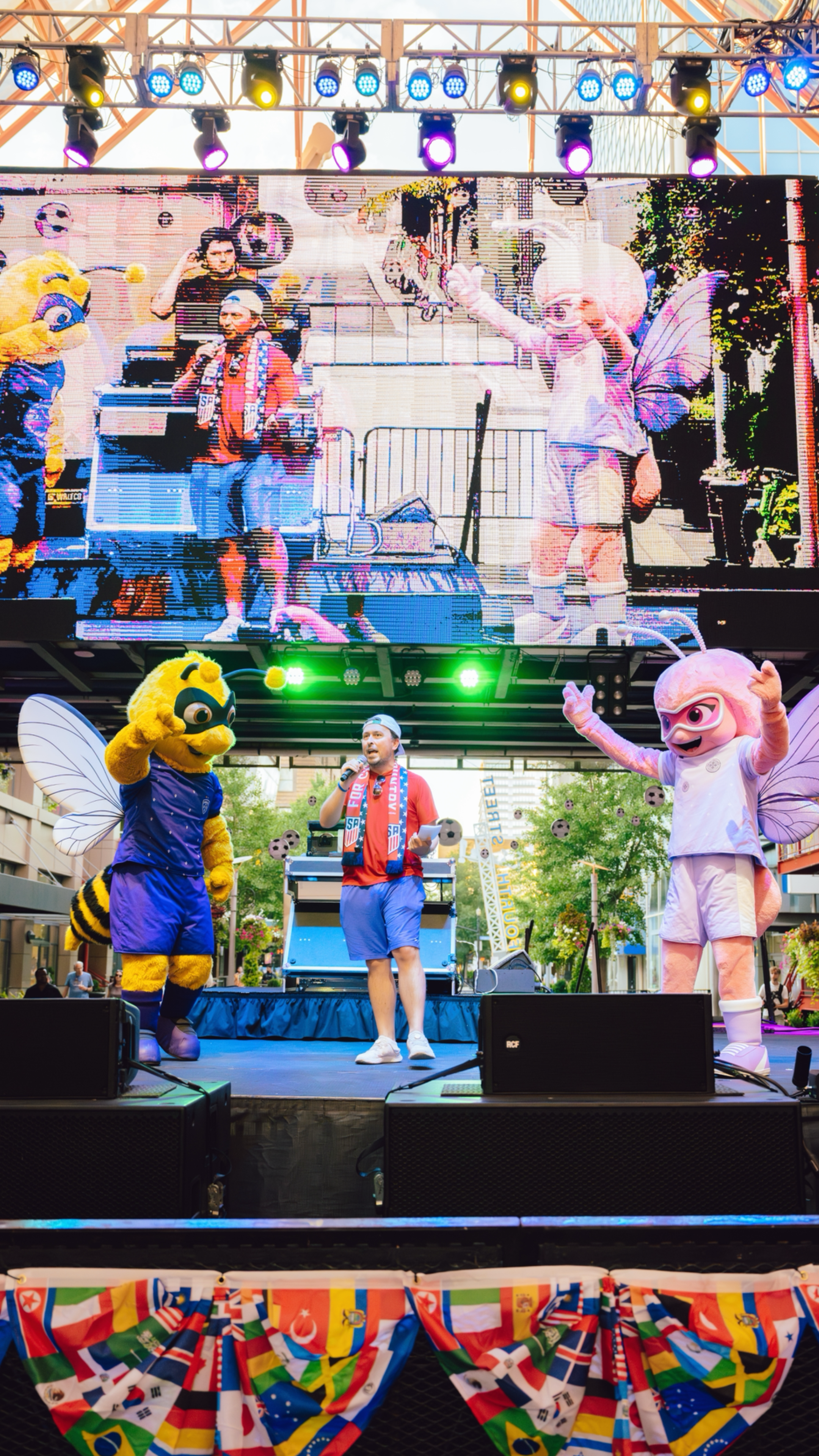 An image of an emcee on stage standing next to two mascots during a World Cup Watch party.