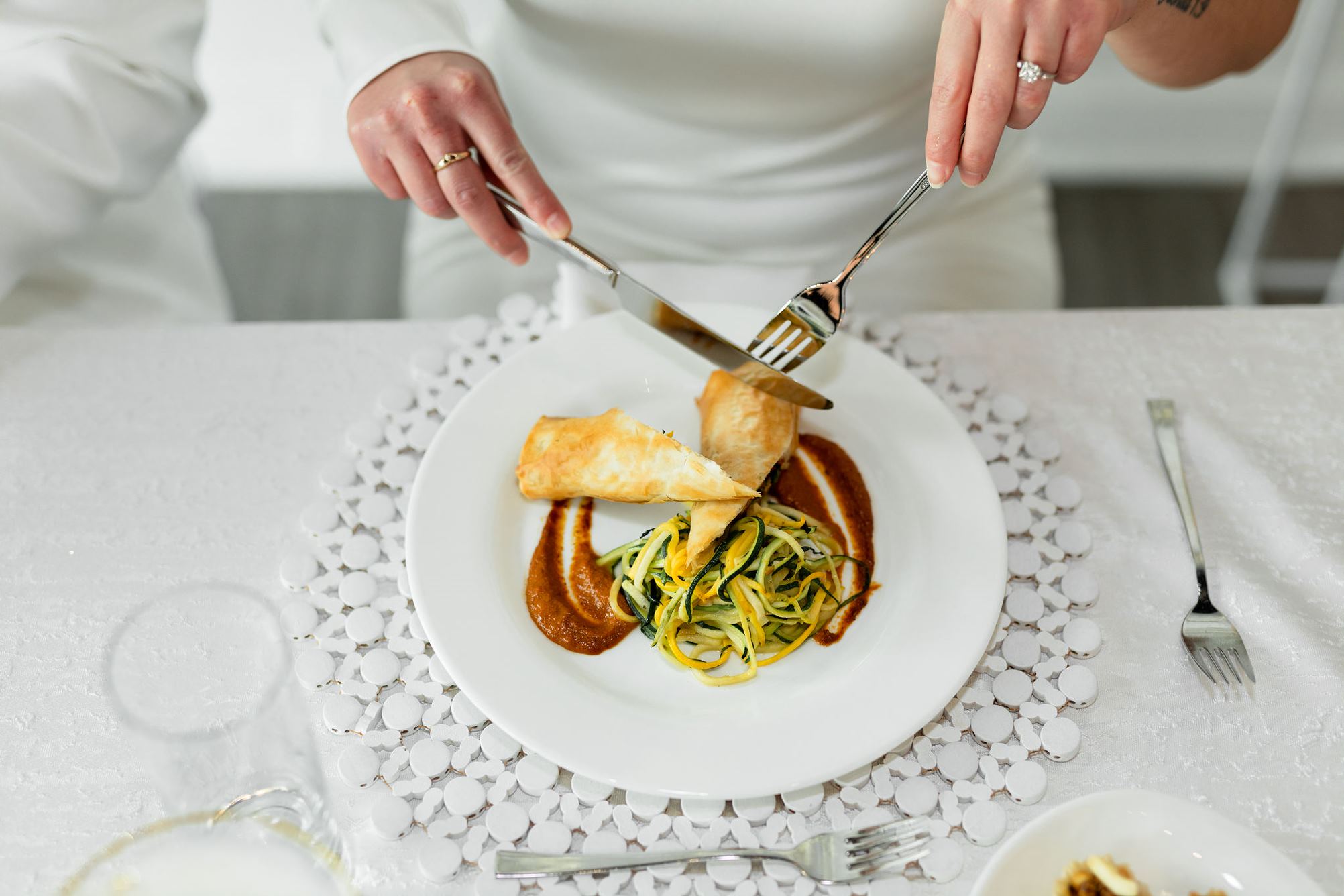 A delicious meal on a white plate on a table with white linens. 