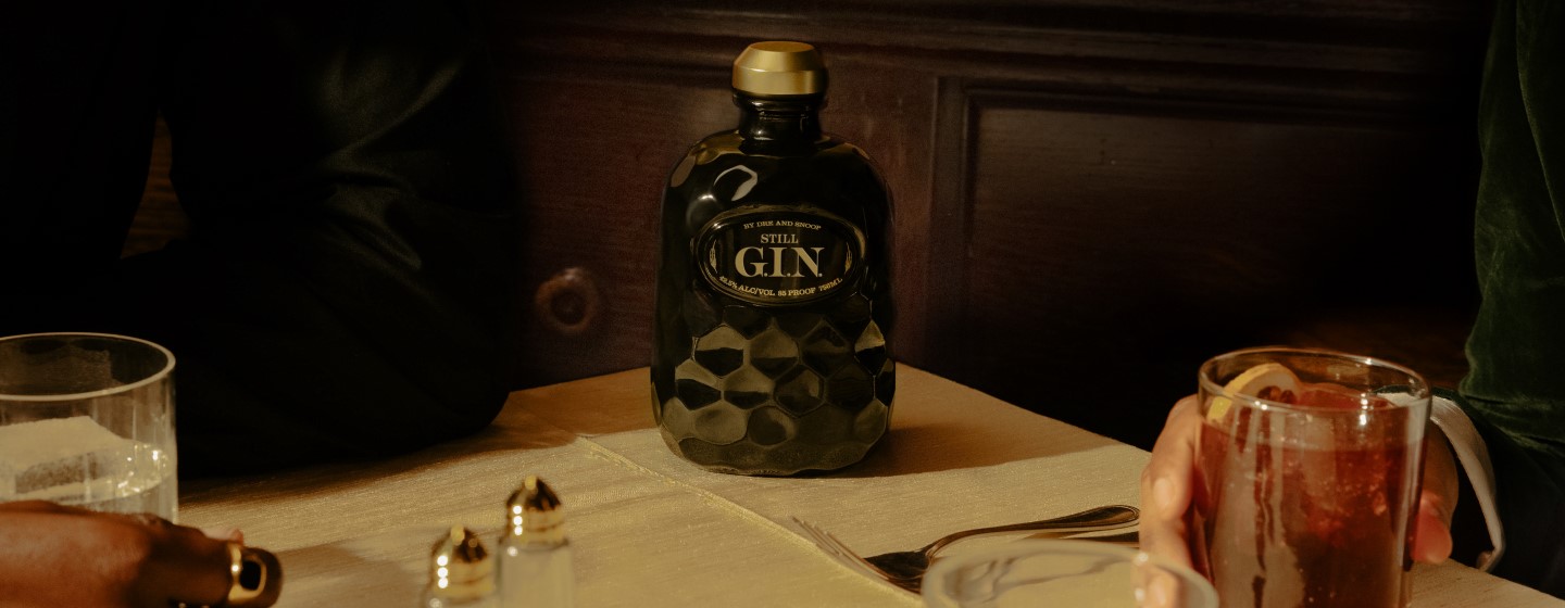 Bottle of Still G.I.N. and cocktails on a table.
