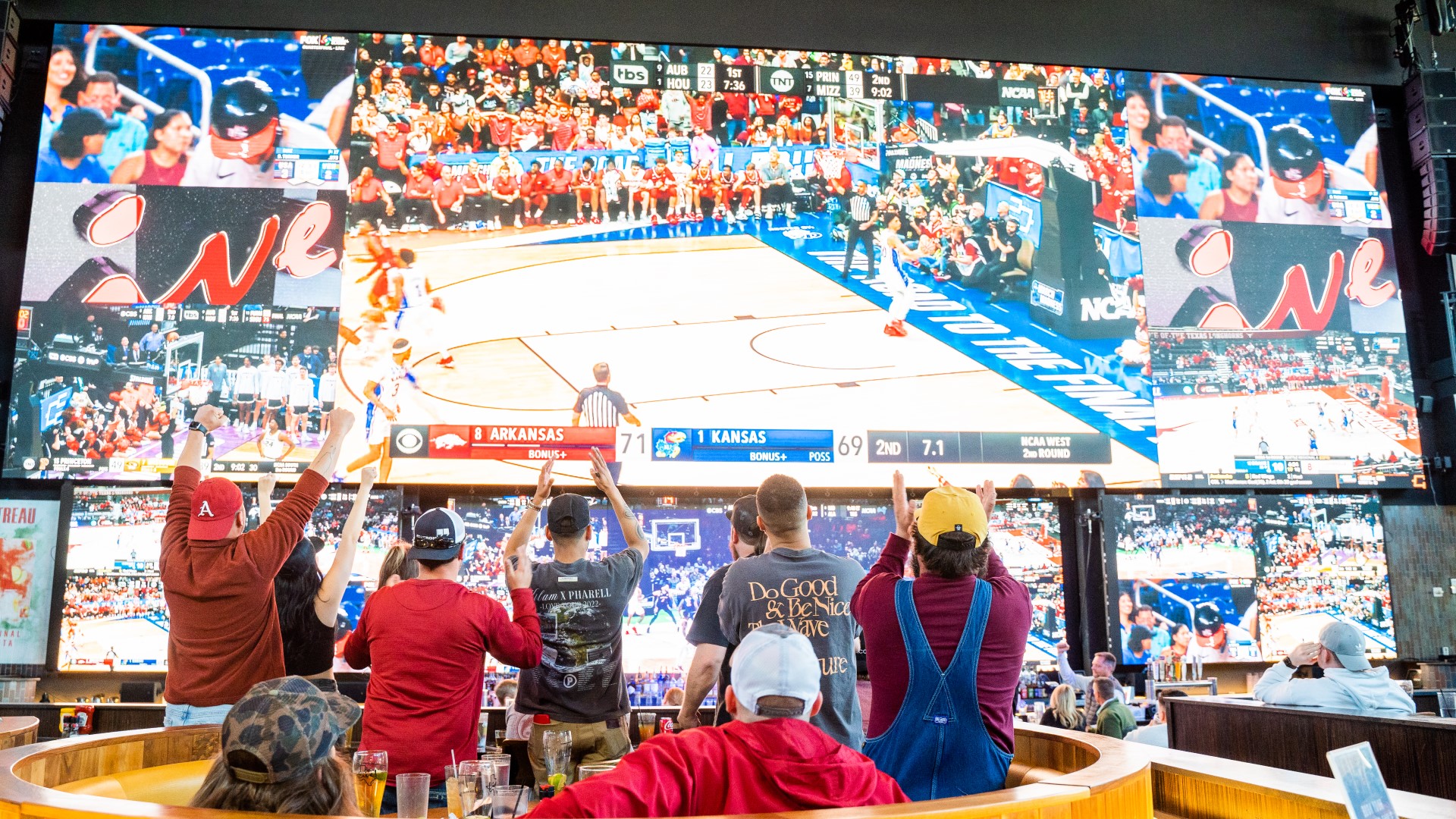 Group of men watching college basketball on media wall at Sports & Social.