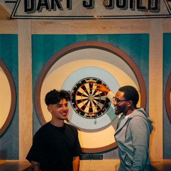 Two male guests playing darts at Sports & Social at Live! at the Pointe Orlando.
