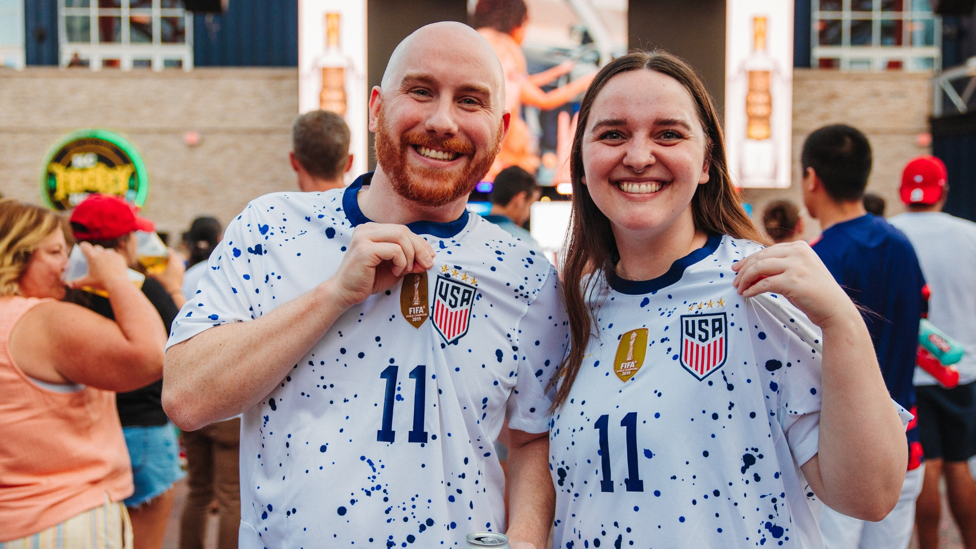 Man and woman couple soccer fans wearing jerseys.