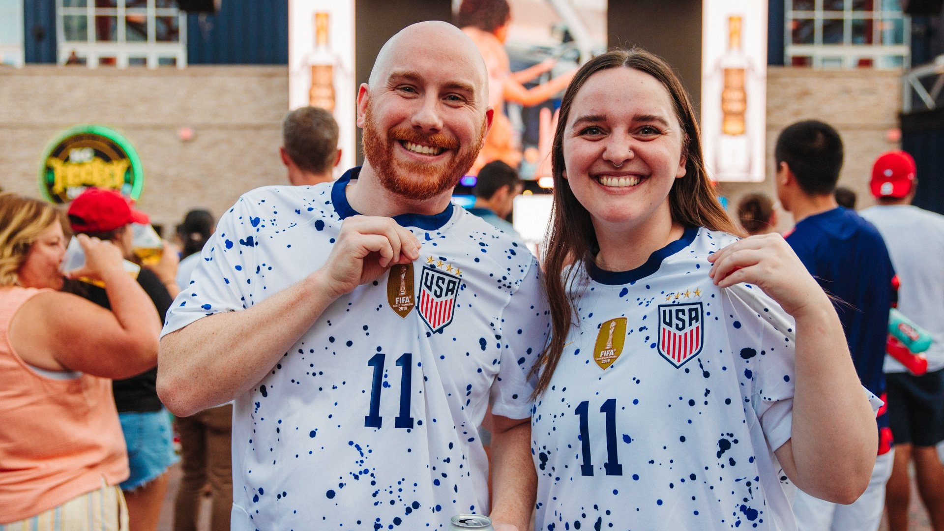 Man and woman couple soccer fans wearing jerseys.