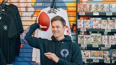 Tom Brady posing with football at CardVault store event.