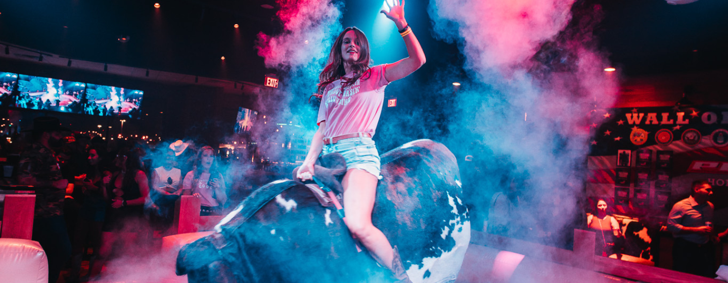 Woman riding mechanical bull at PBR Cowboy Bar.