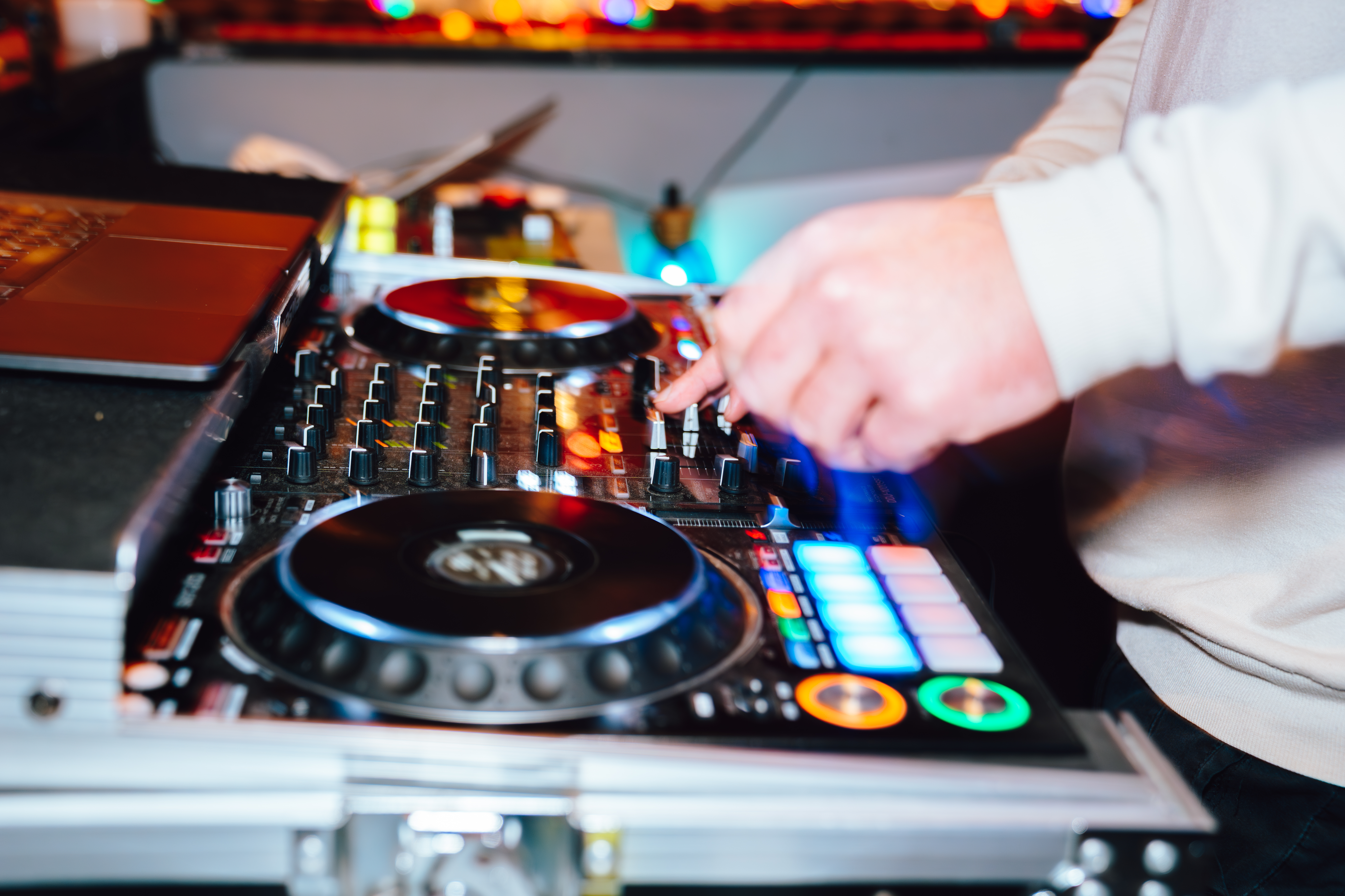 A close up image of a turntable with a DJ playing and his hands on the turntable.