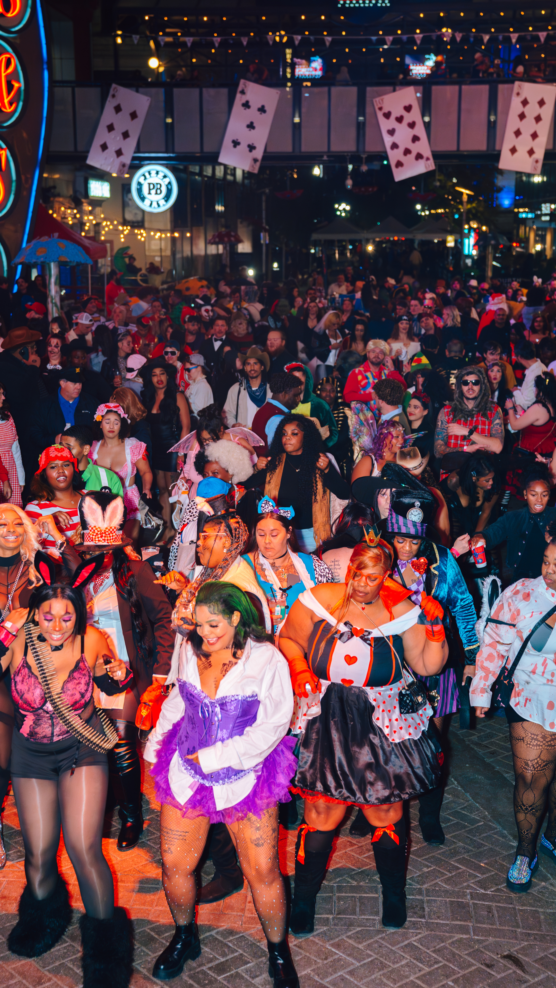 An image of a bunch of party goers dressed in Halloween costumes and dancing.