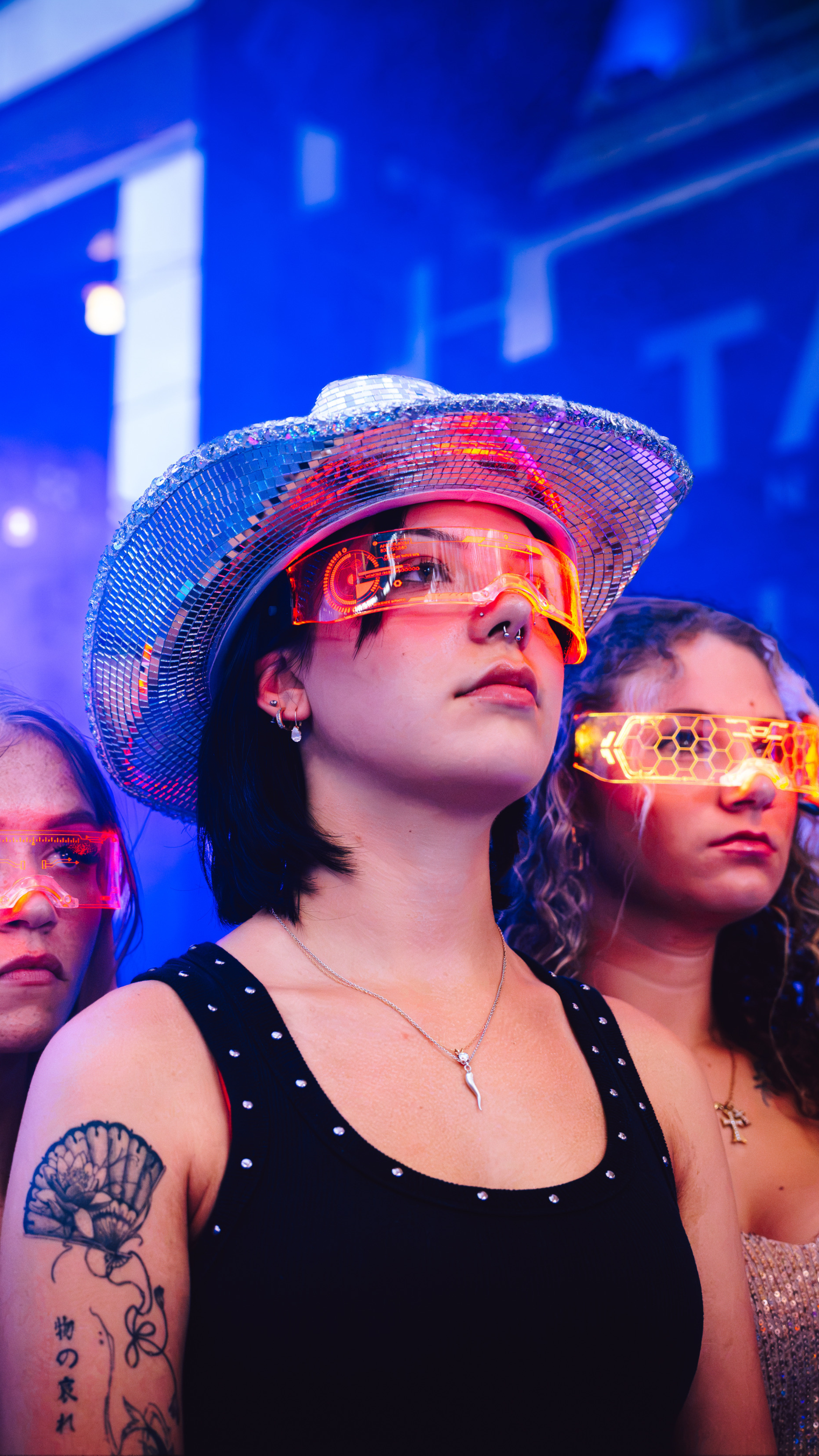 AN image of 3 girls wearing light up tech glasses.