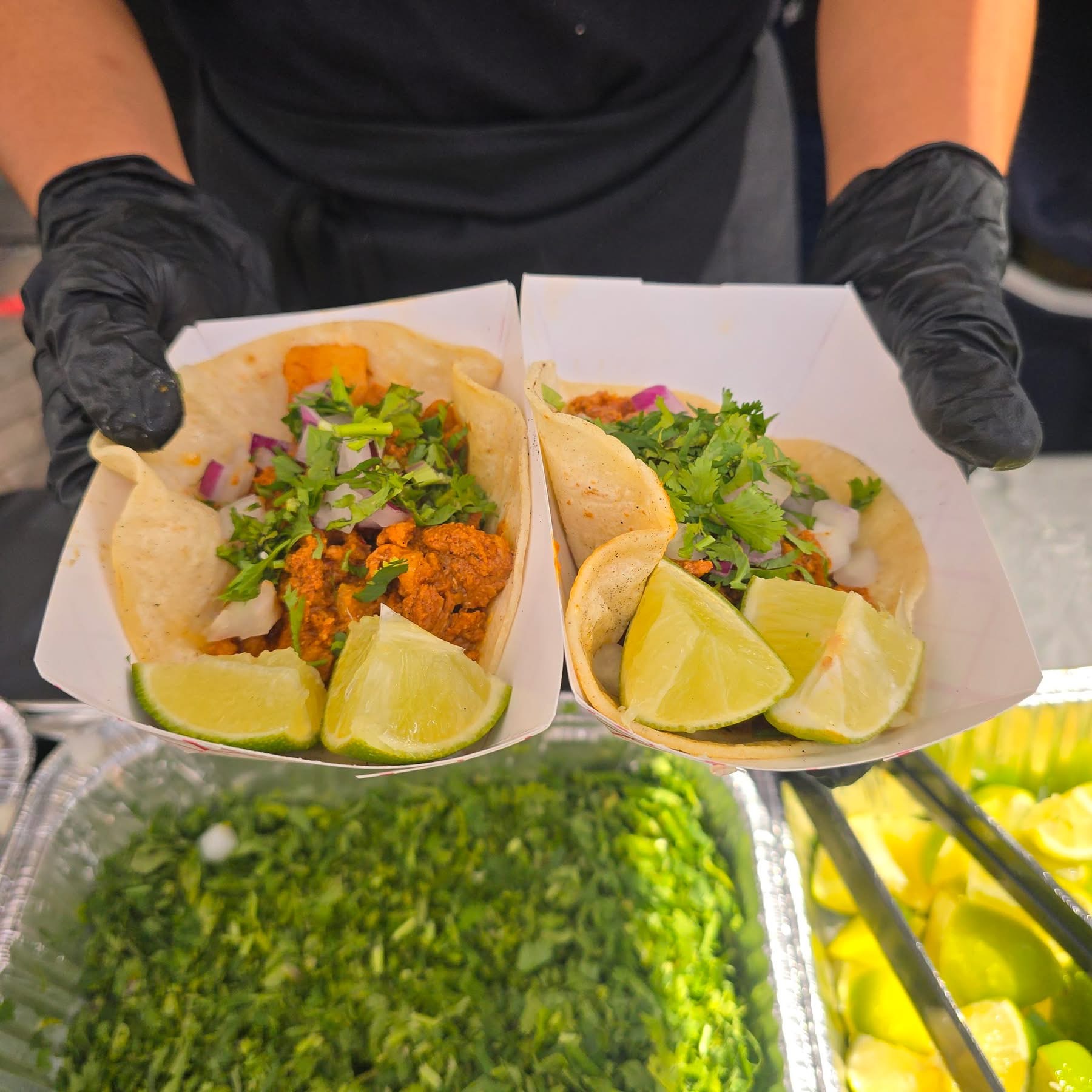 Image of employee holding out tacos at the taco festival.