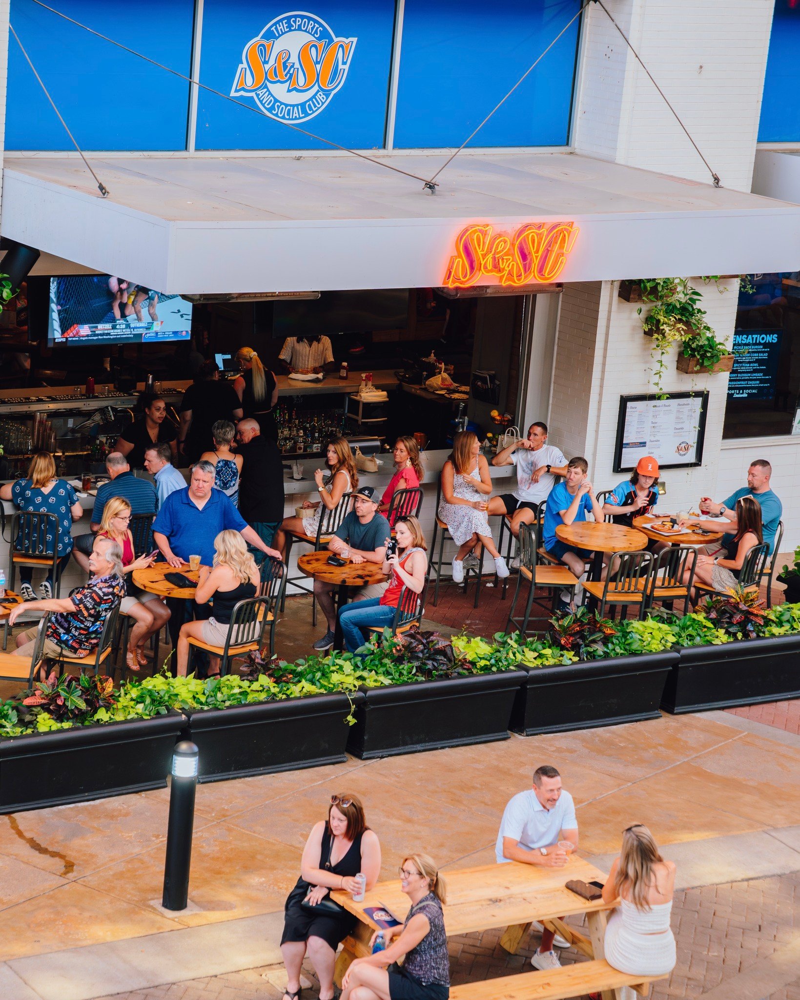 A wide view shot of the entire Sports and Social patio filled with people sitting at tables.