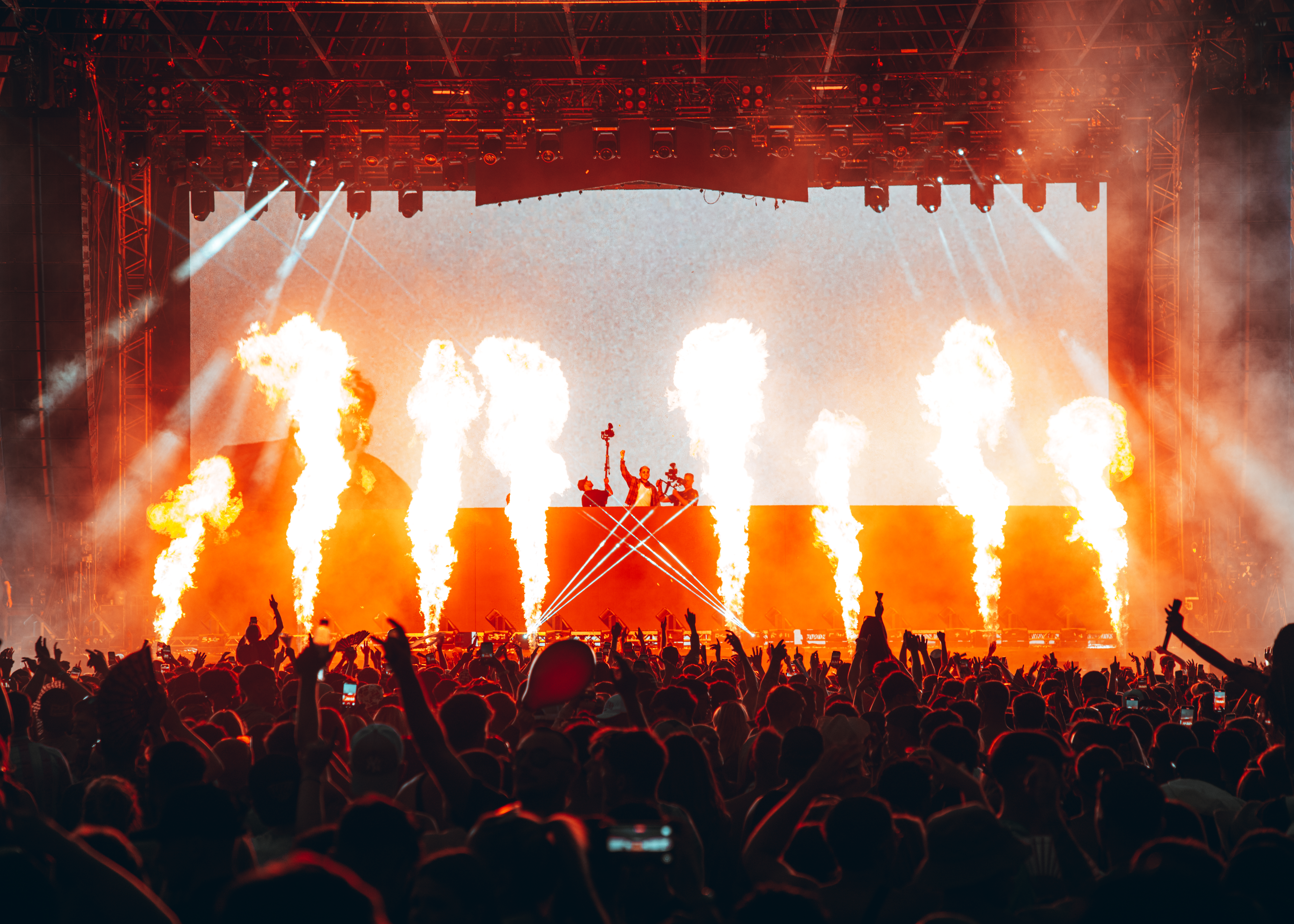 An image from D.O.D. playing live on a stage with flames rising from the stage and a packed crowd in front.