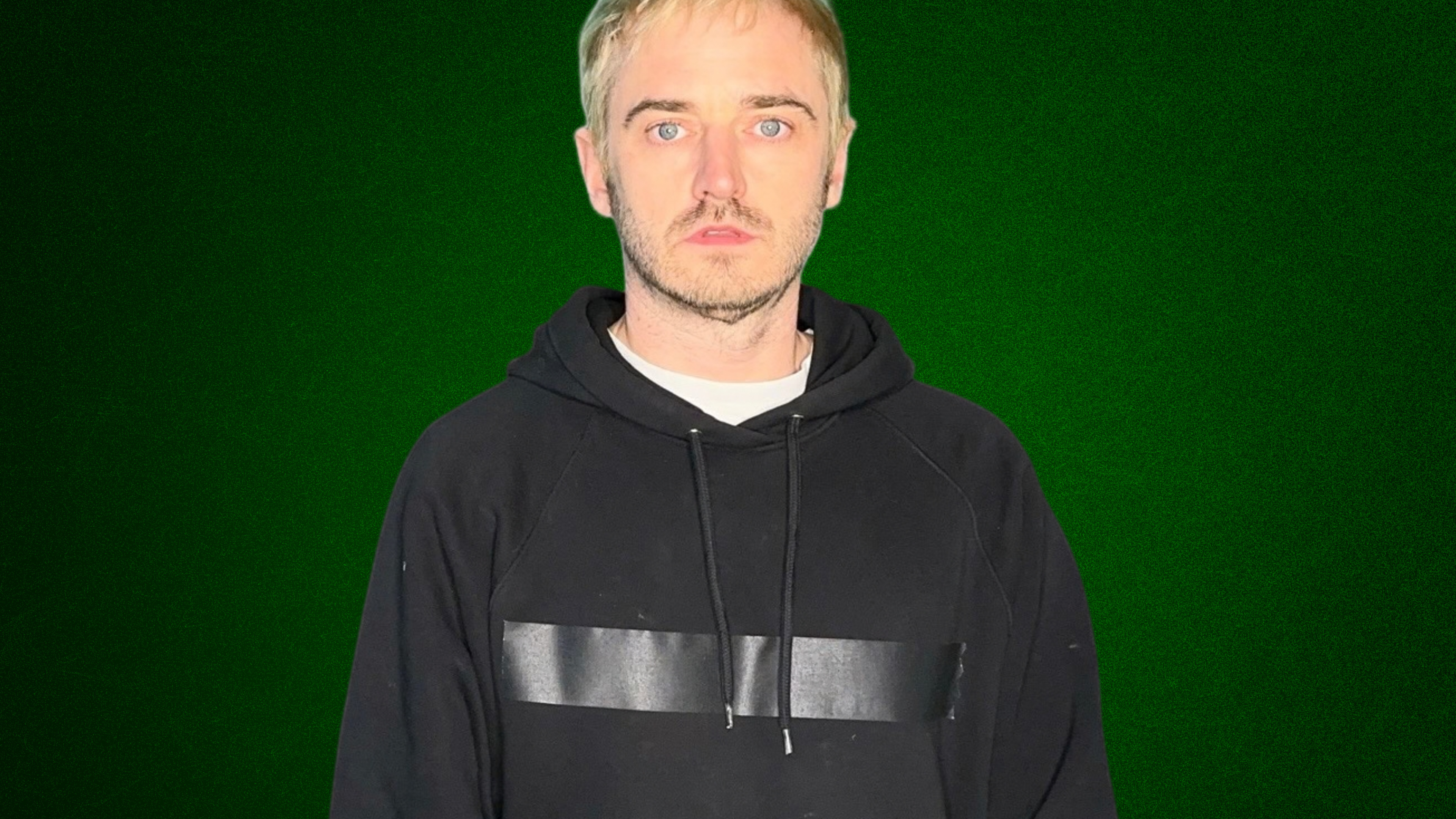 An image of a man, Junior, wearing a black hoodie and looking straight into the camera, with a green background.