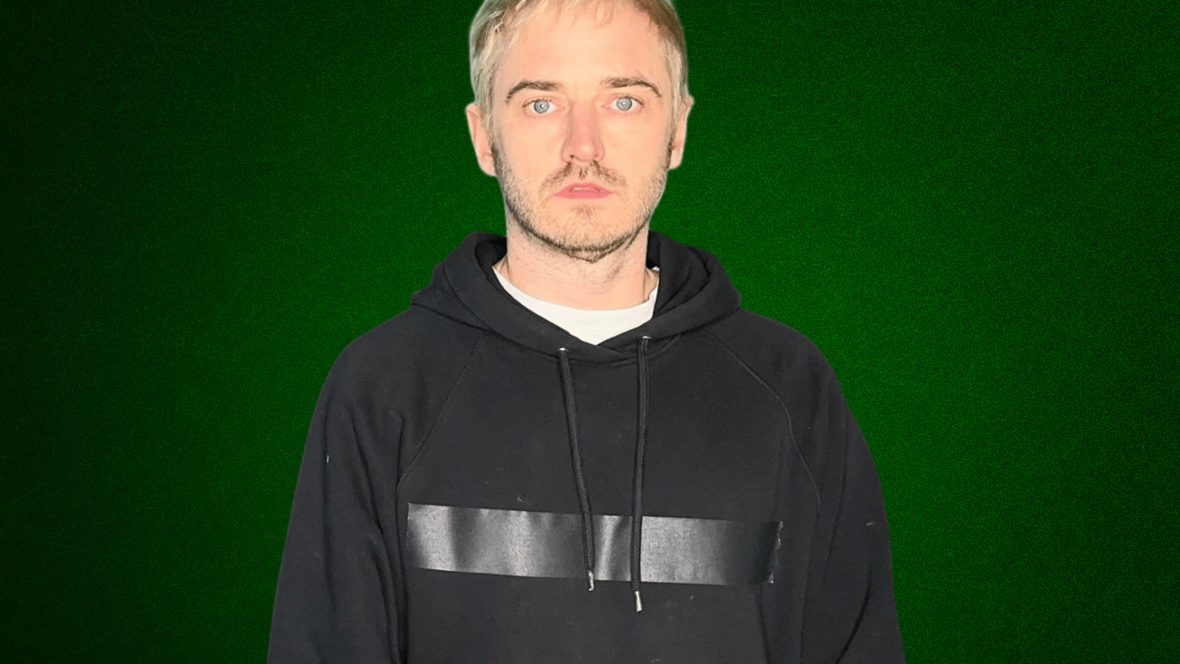 An image of a man, Junior, wearing a black hoodie and looking straight into the camera, with a green background.