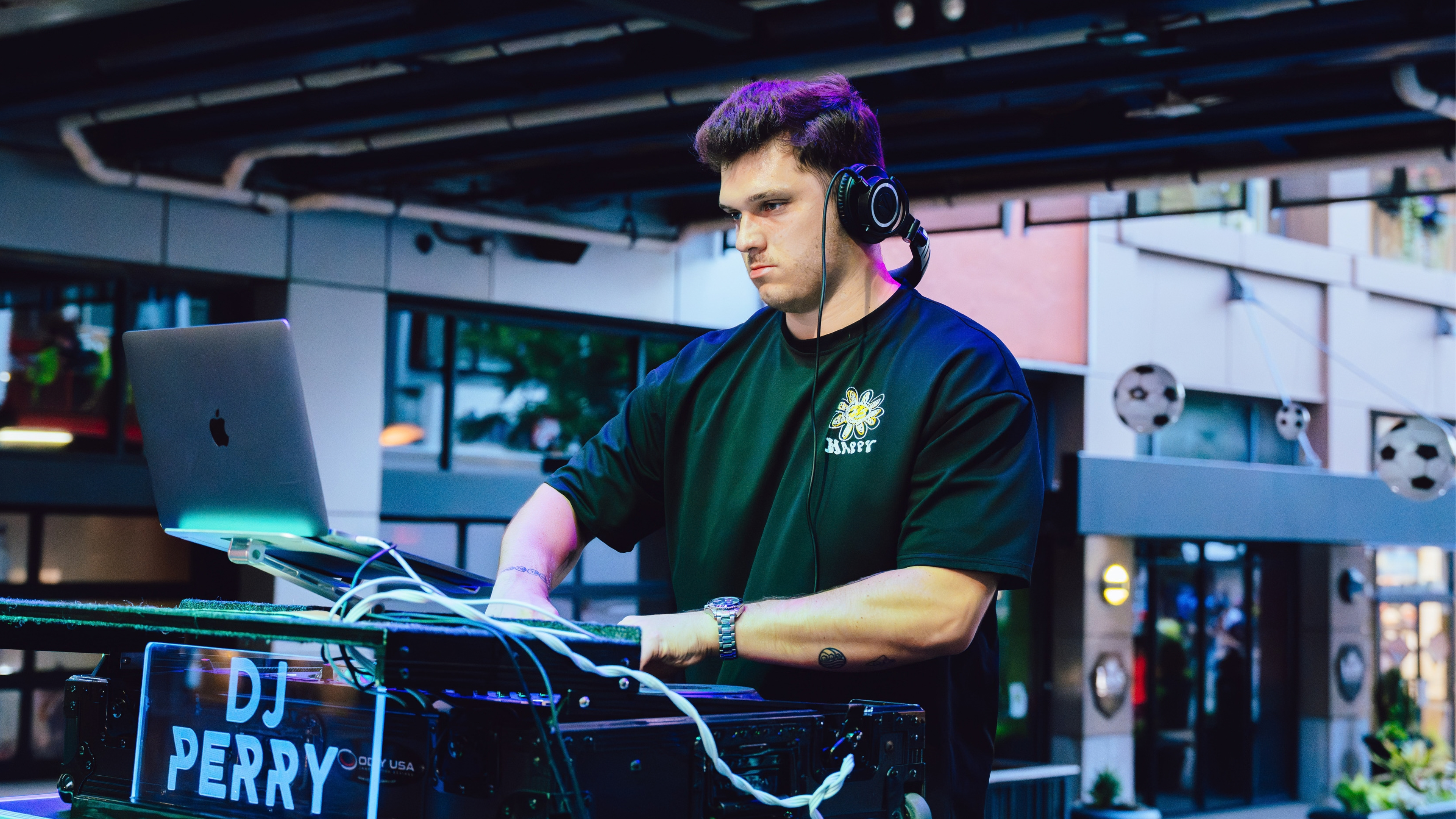 An image of a man, DJ Perry, wearing a black shirt and djing.